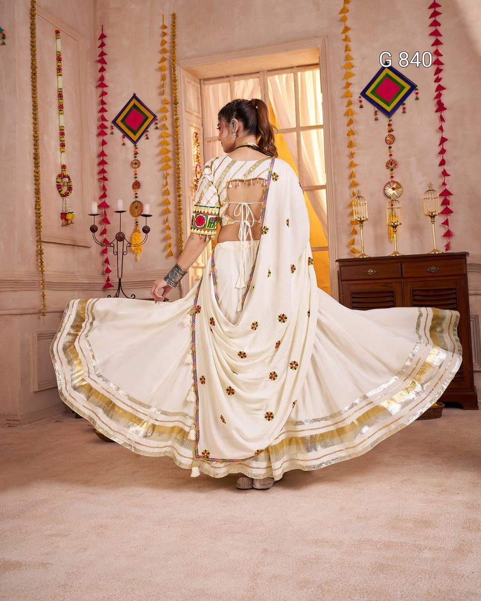 Woman in a white saree with gold details in a decorated room.