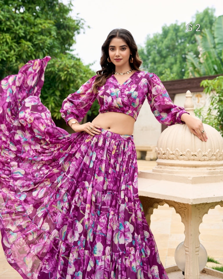 Woman in a purple floral outfit standing outdoors with greenery in the background