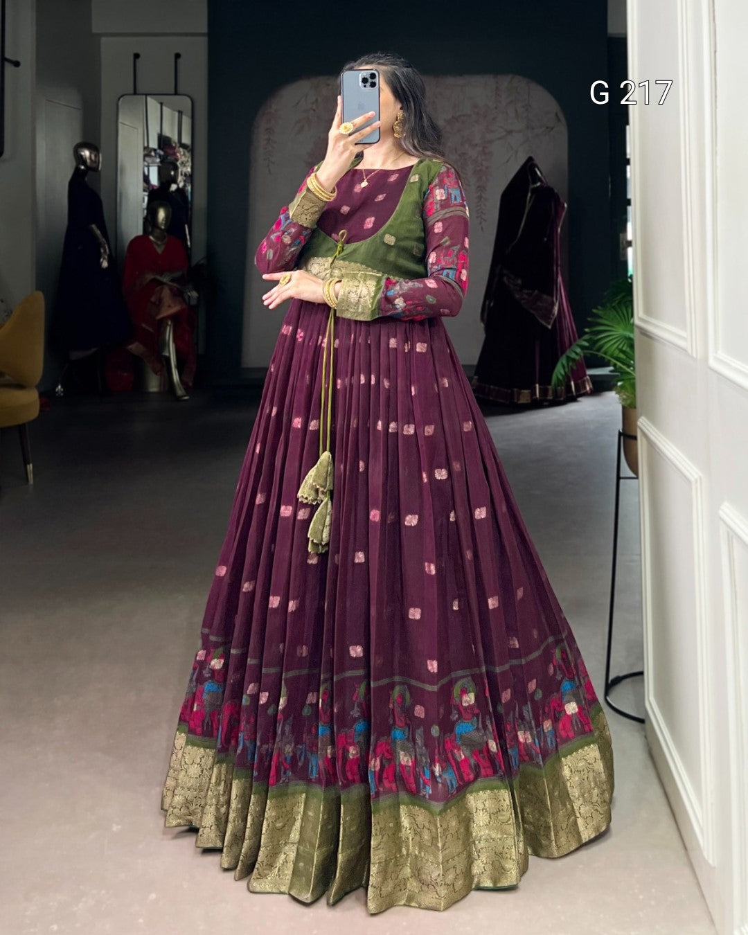 Woman wearing a traditional maroon and green outfit with floral patterns indoors.