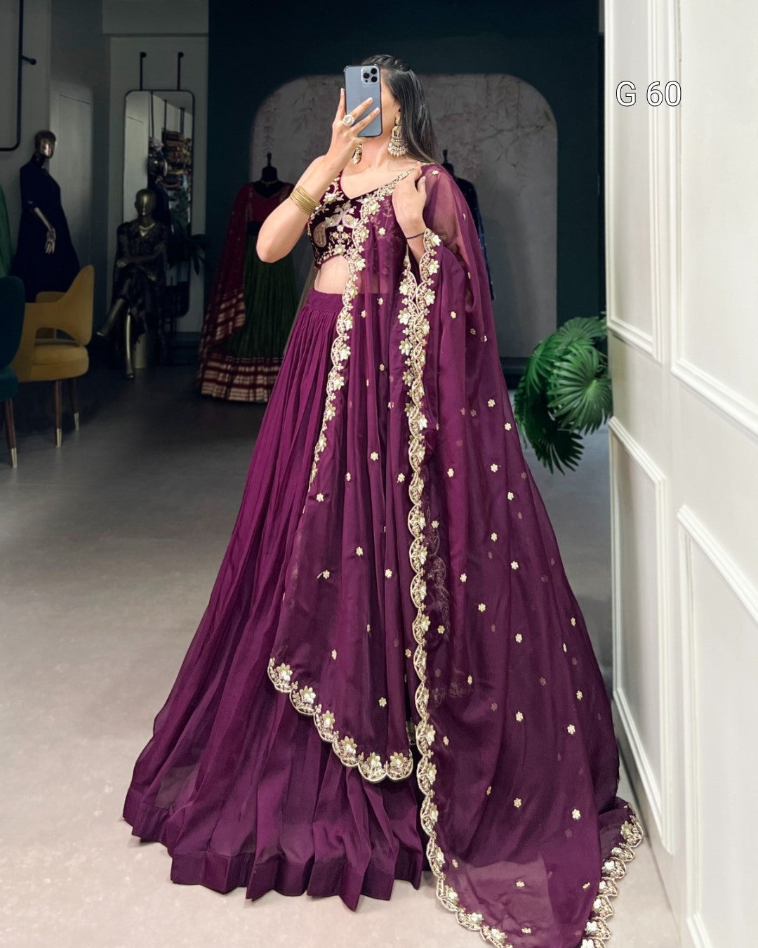 Person wearing a purple traditional outfit with intricate designs in a room.