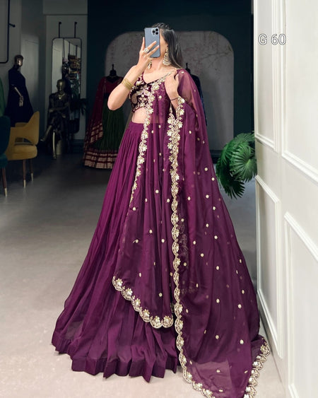 Person wearing a purple traditional outfit with intricate designs in a room.