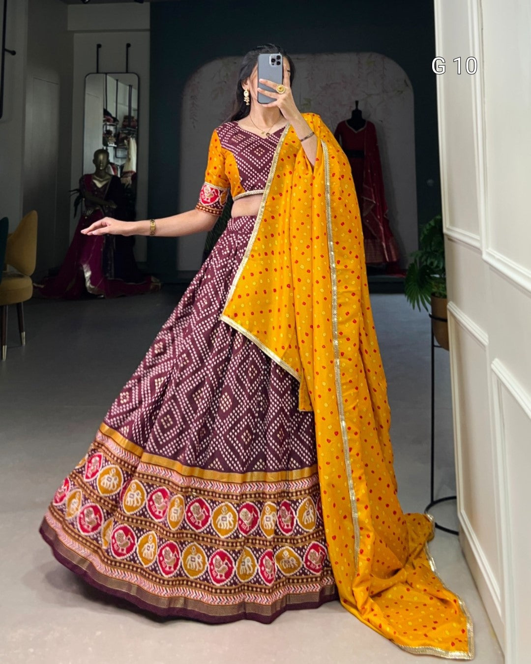 Person wearing a traditional maroon and yellow saree with a patterned design indoors.