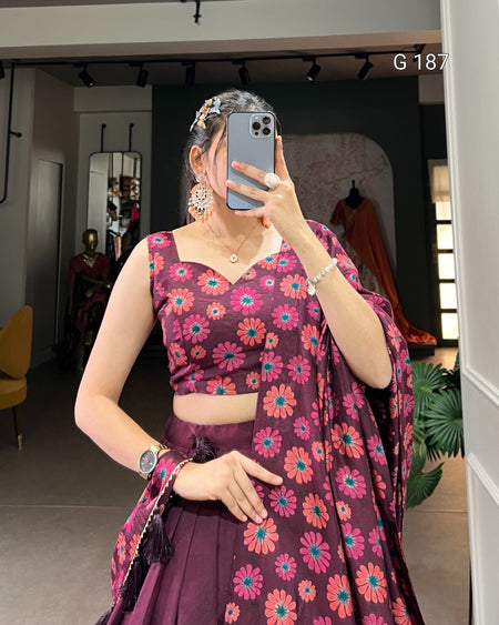Person wearing a floral purple outfit taking a mirror selfie.