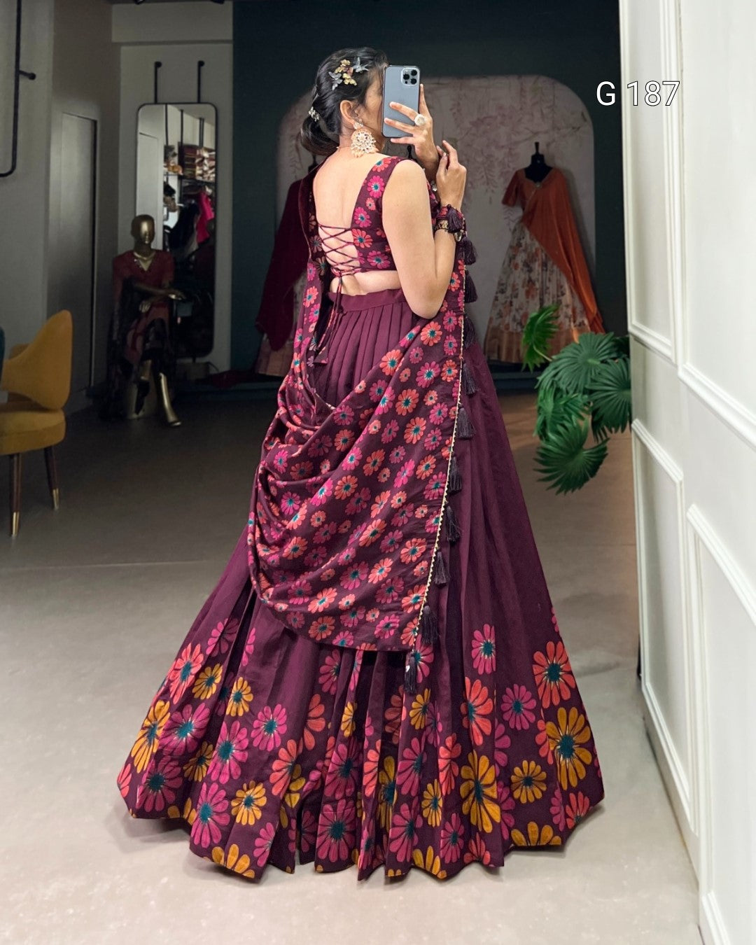 Person wearing a floral saree taking a mirror selfie in a room.