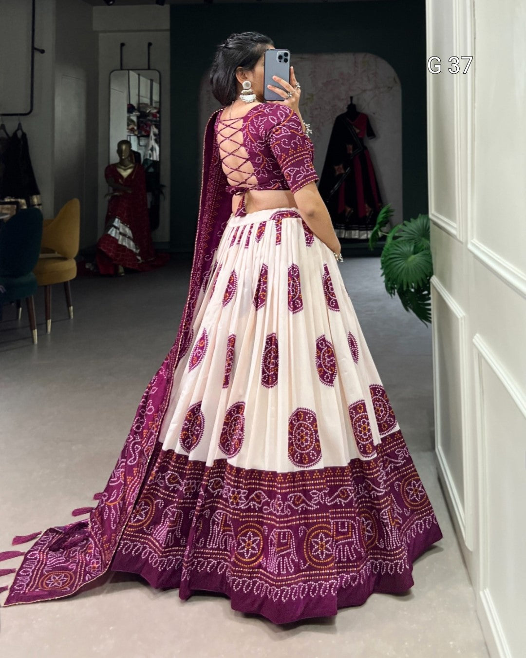 Person wearing a traditional purple and white embroidered outfit in a room.