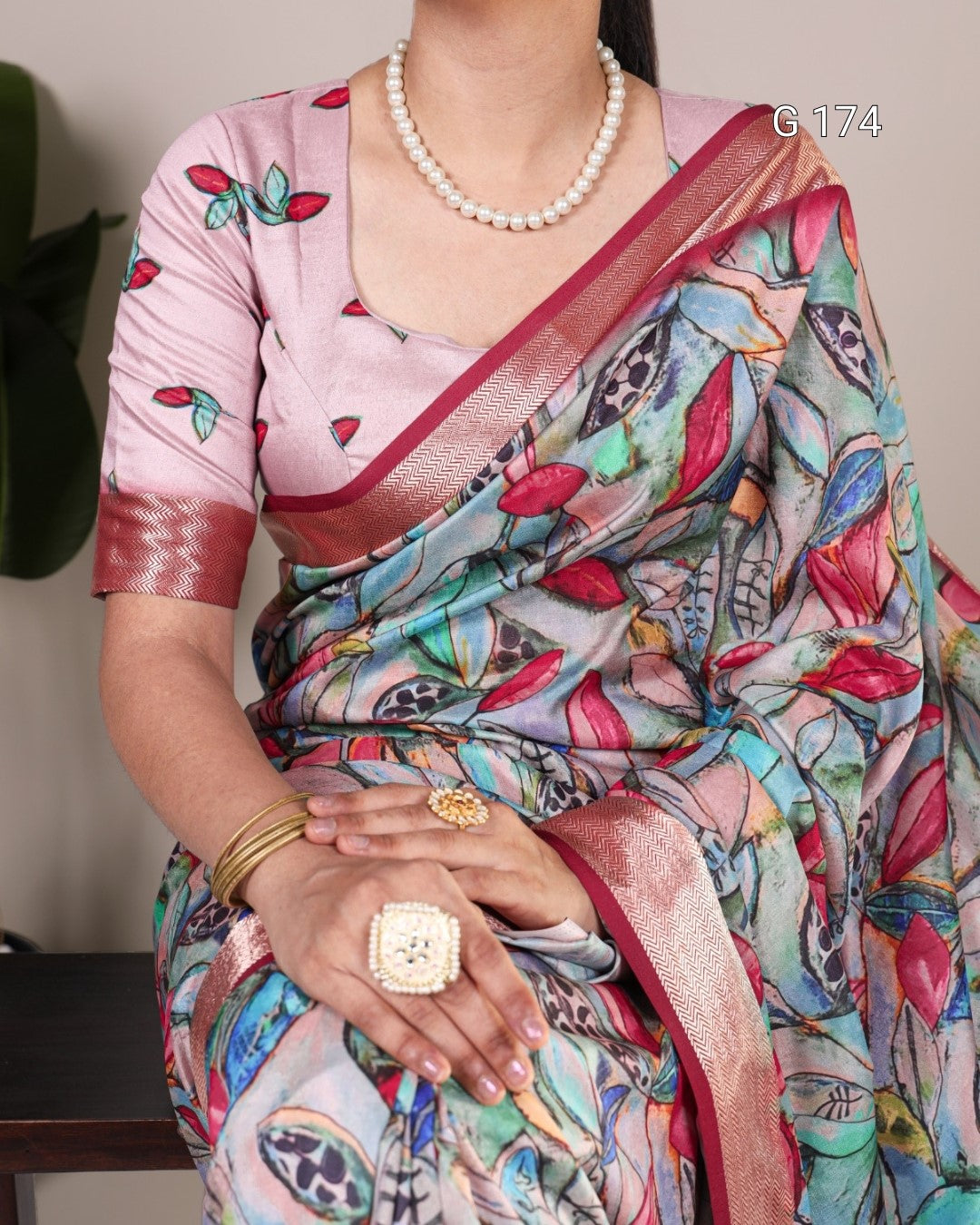 Person wearing a colorful saree with a pink blouse, holding hands together.