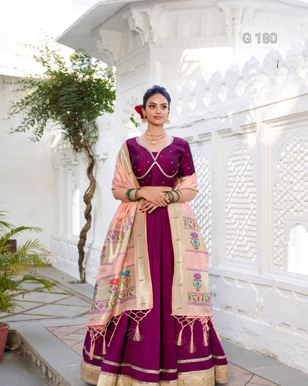 Woman in a traditional outfit with a purple and beige saree in an outdoor setting.