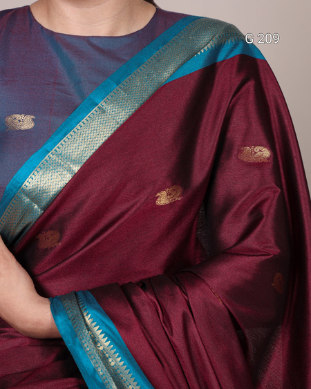 Maroon saree with blue border draped over a person, on a plain background