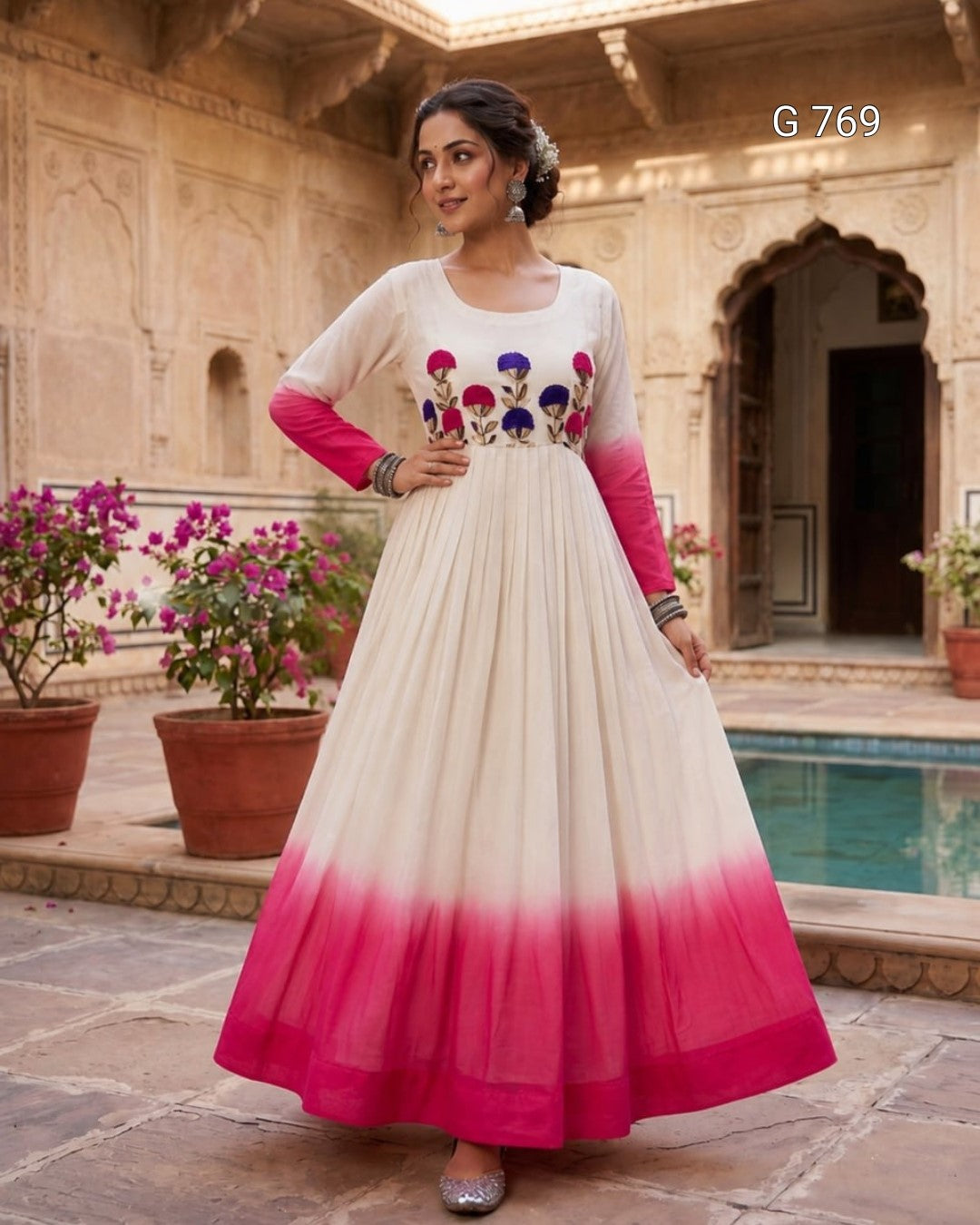 Woman in a white and pink dress with floral embroidery standing in an outdoor setting.
