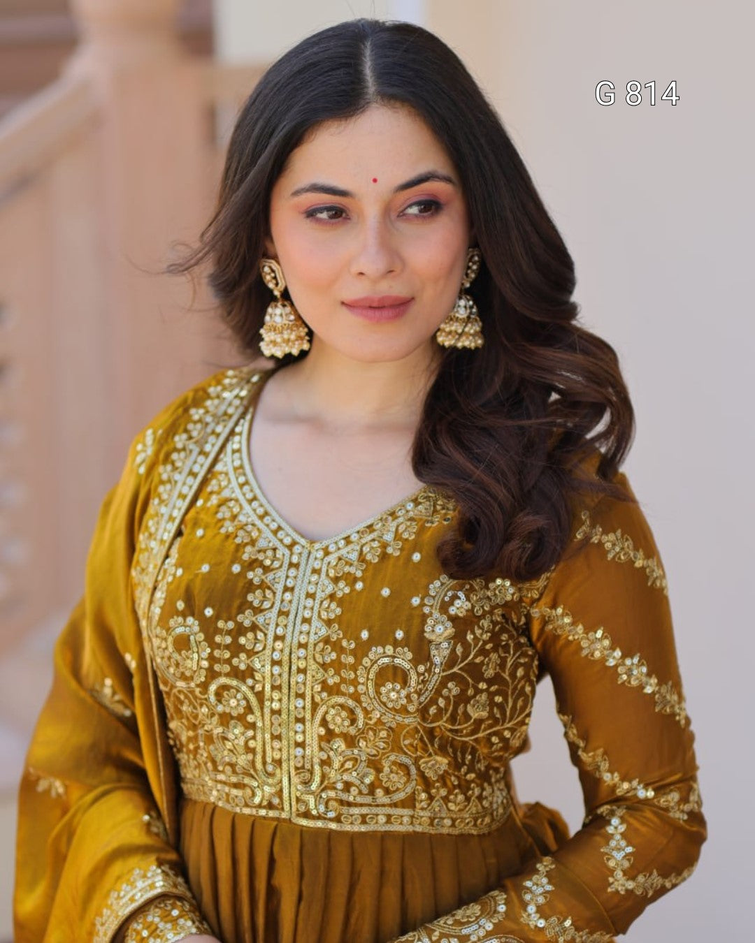 Woman wearing a mustard yellow traditional outfit with gold embroidery.