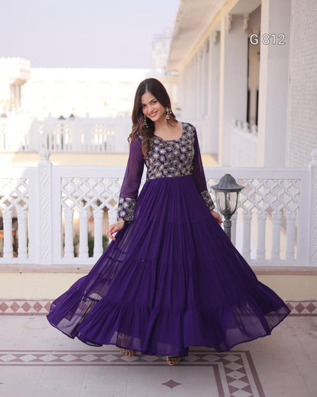 Woman wearing a purple and black dress standing on a balcony.