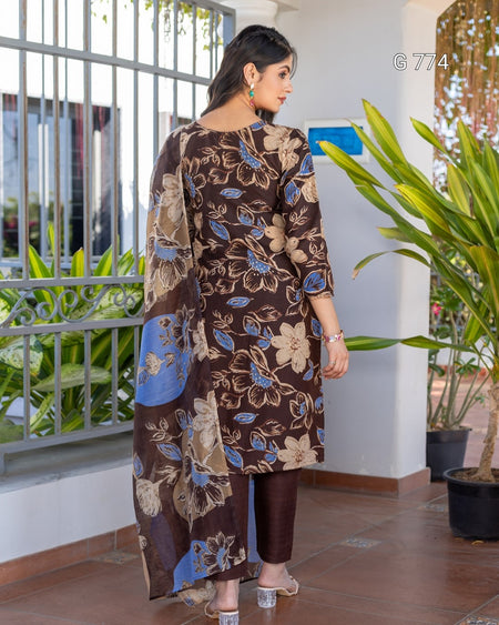 Woman wearing a brown floral dress standing in front of a window with plants.