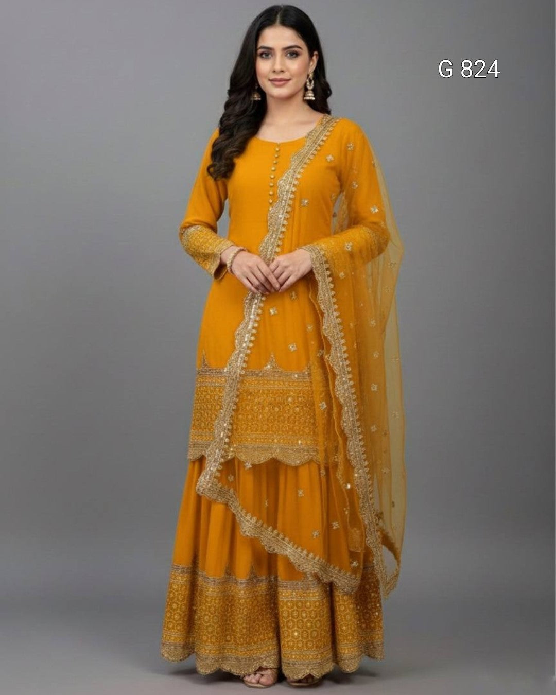 Woman wearing a mustard yellow traditional outfit with gold embroidery on a gray background