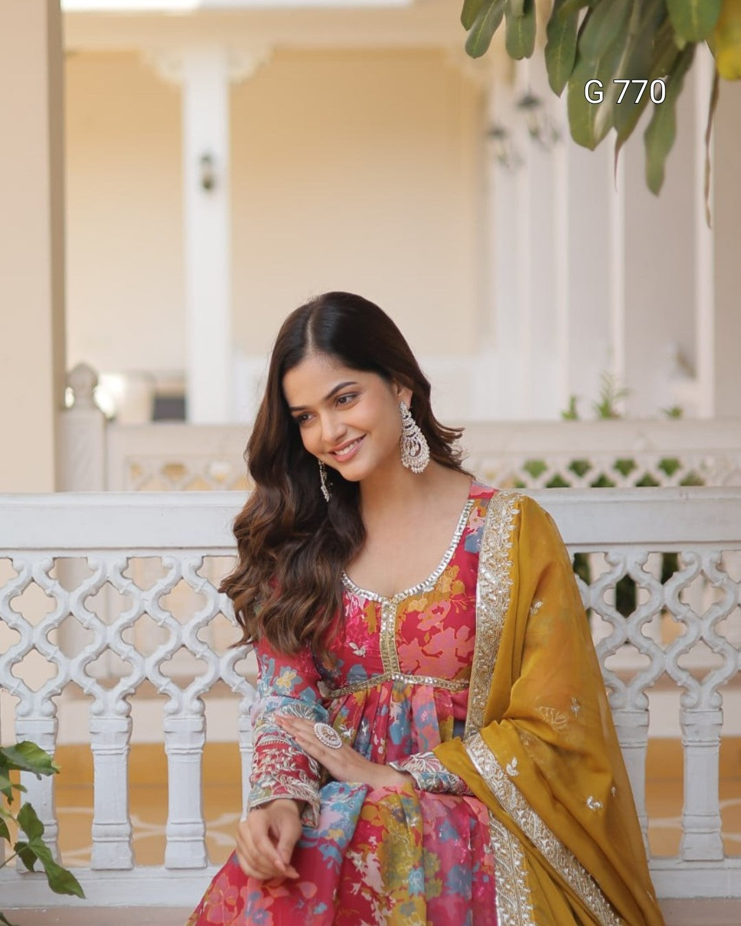 Woman in a colorful traditional outfit sitting on a white bench with a blurred background