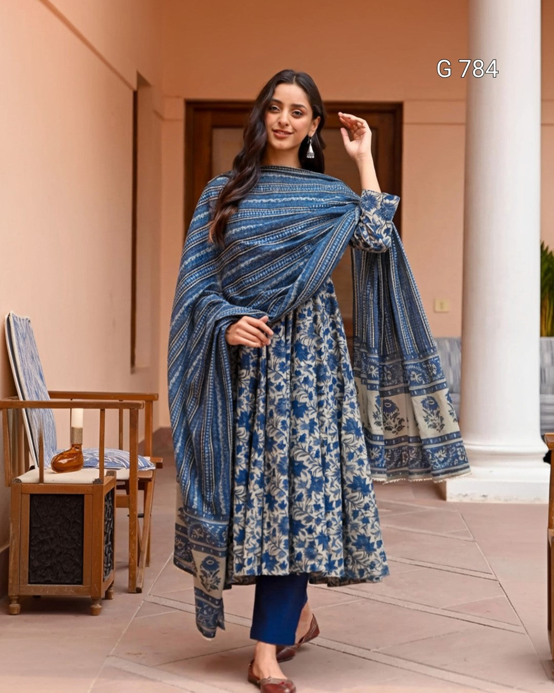 Woman wearing a blue and white patterned traditional outfit in an indoor setting.
