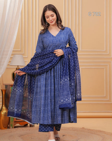 Woman wearing a blue patterned dress with a matching dupatta in a room with beige walls.