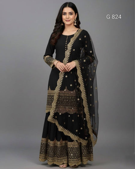 Woman wearing a black and gold traditional outfit with a sheer dupatta on a gray background