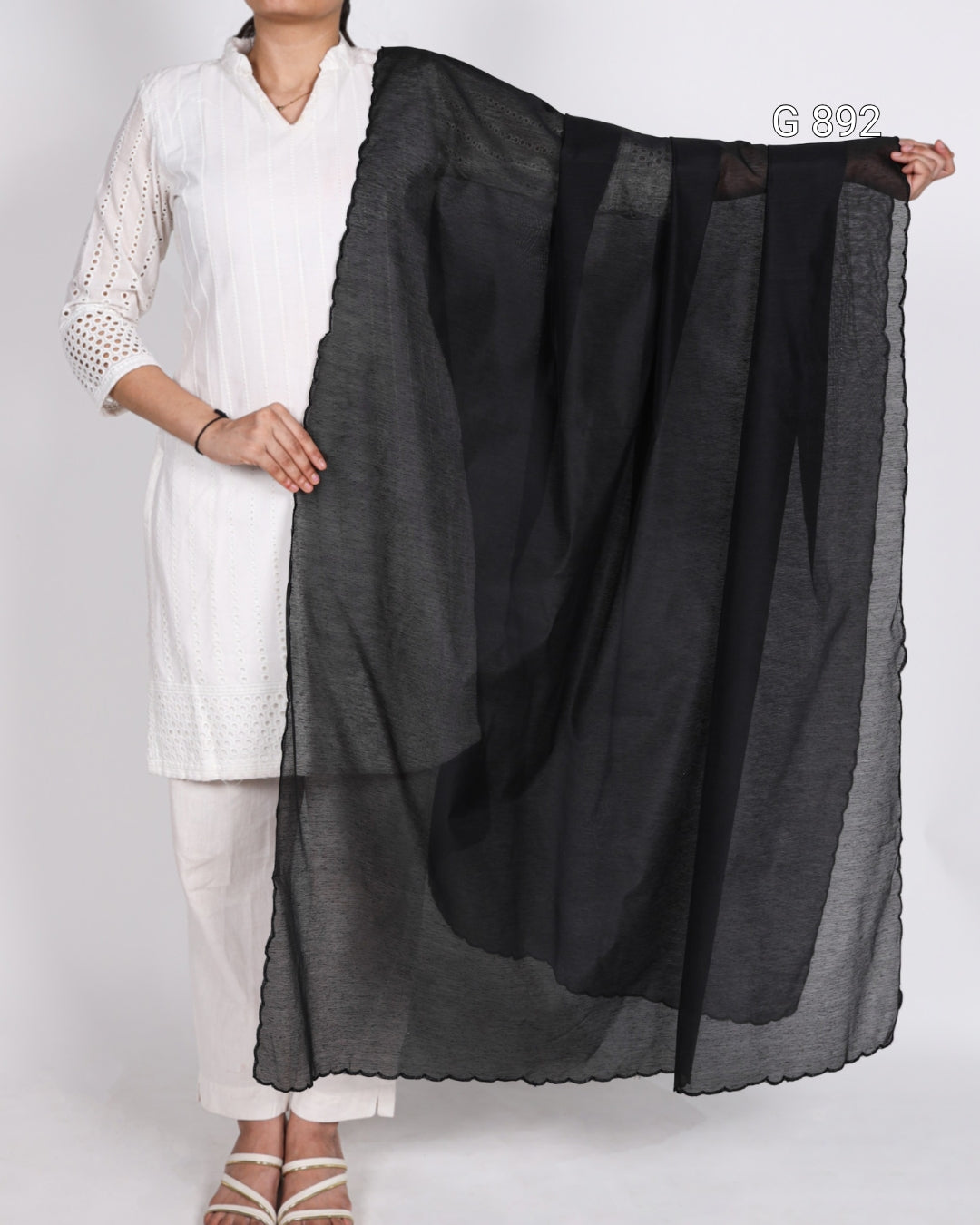 Person holding a black scarf against a white background