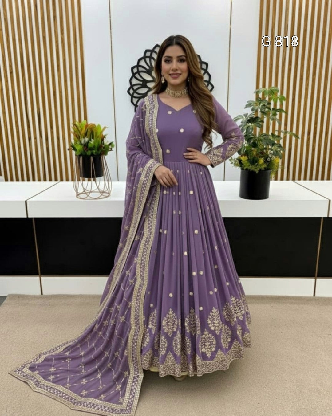 Woman in a purple traditional outfit with gold embroidery standing indoors.