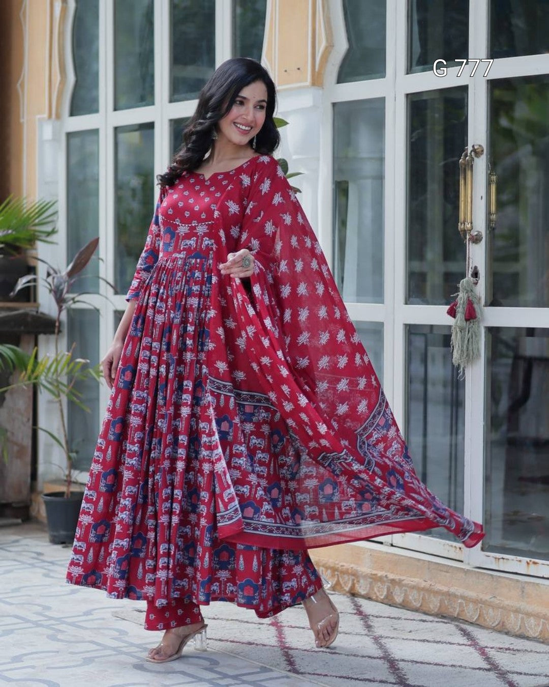 Woman in a red and blue patterned dress standing in front of a glass door.