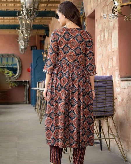 Woman wearing a patterned dress in an indoor setting with decorative elements.