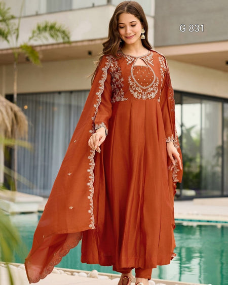 Woman wearing a rust-colored embroidered dress by a poolside
