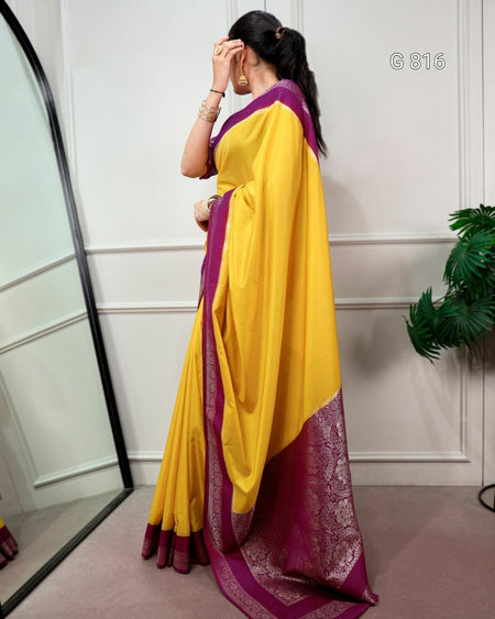Woman wearing a yellow and purple saree with a white wall background