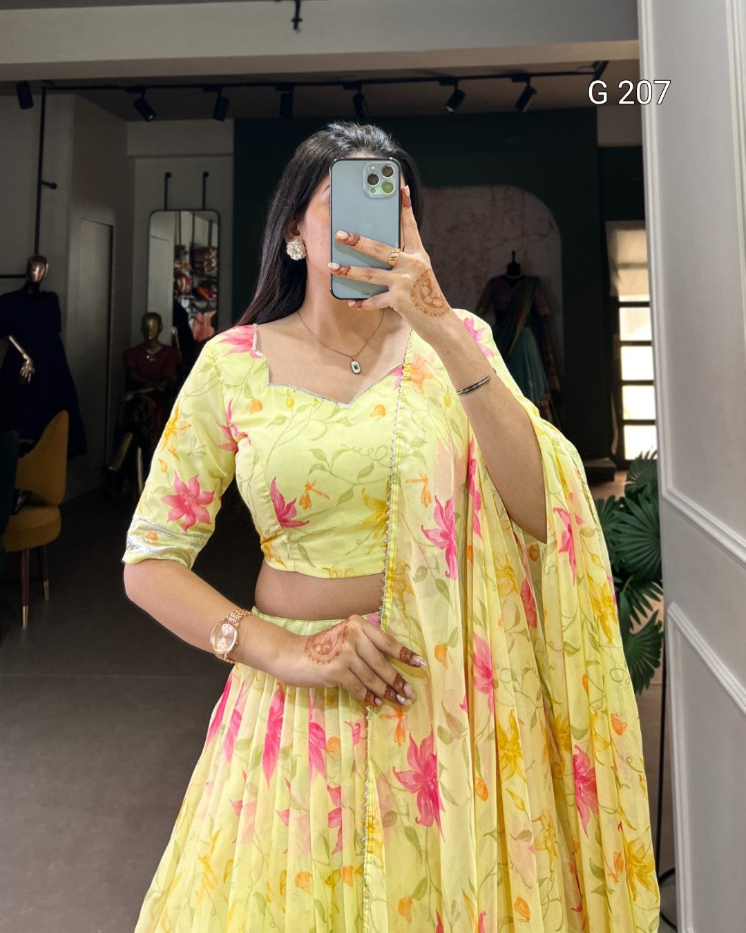 Person wearing a yellow floral outfit taking a mirror selfie.