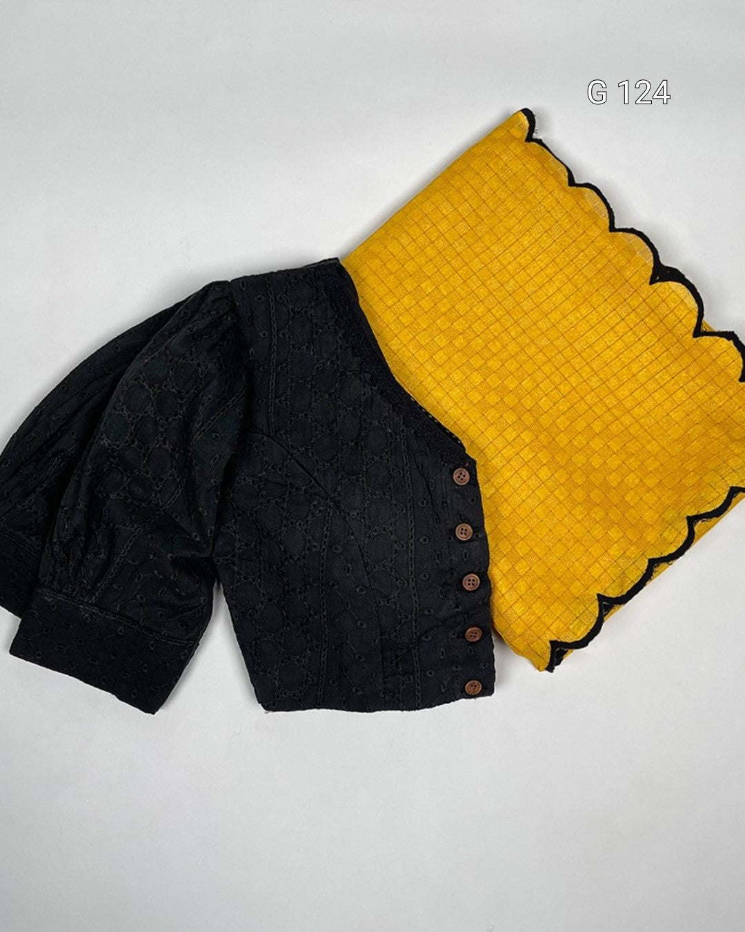 Black cardigan with yellow quilted blanket on a light gray background