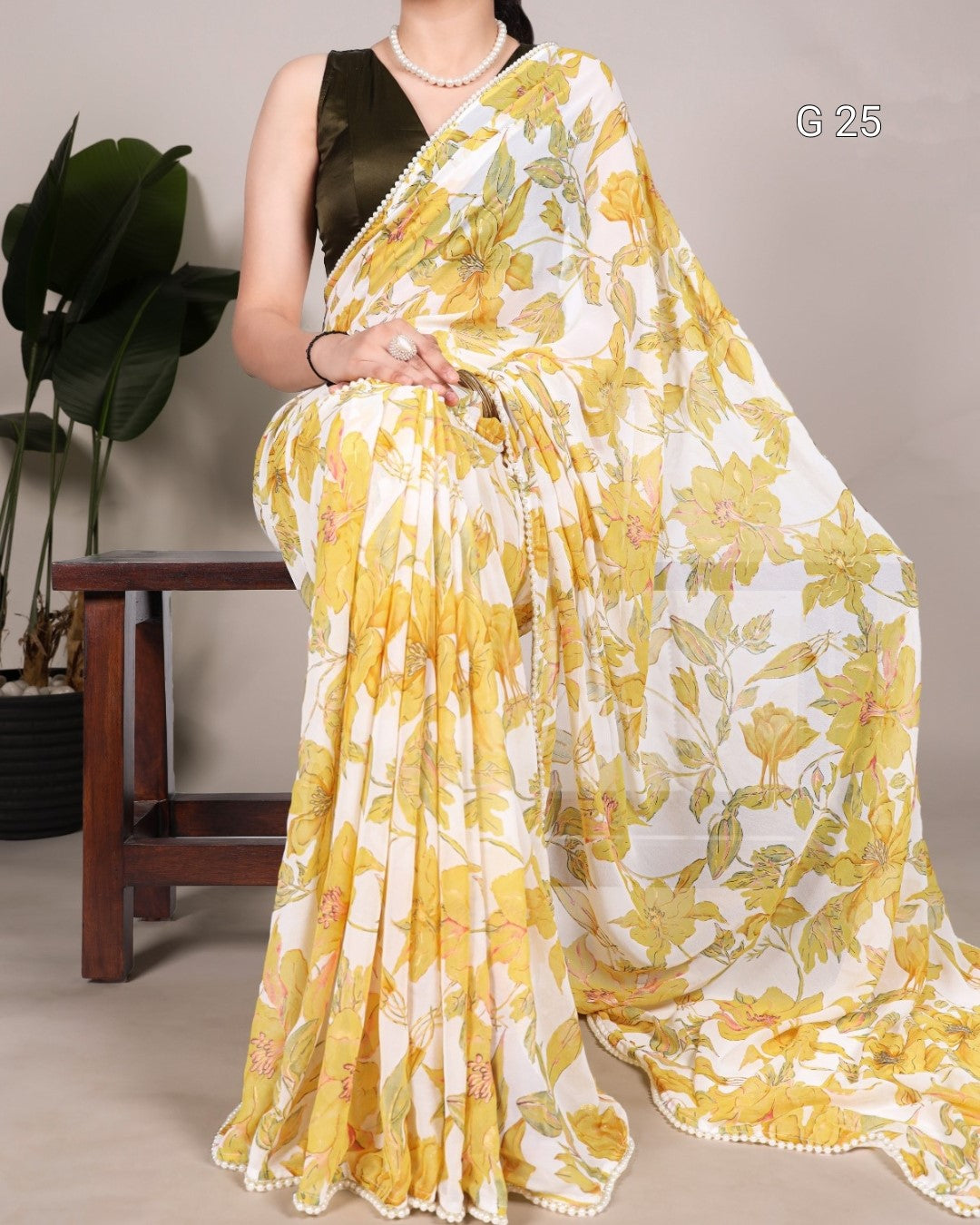 Woman wearing a yellow and white floral saree with a plant in the background