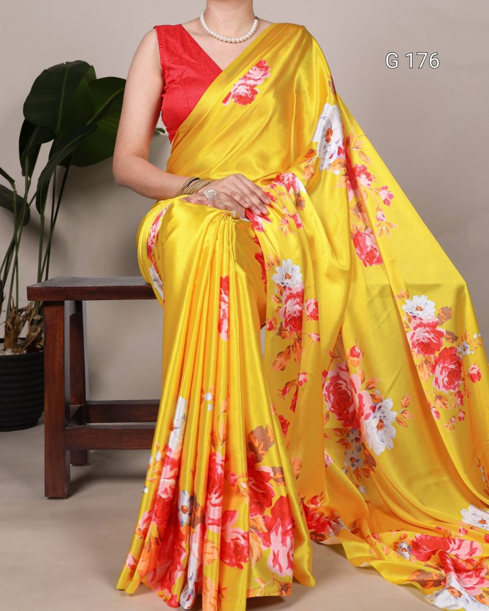 Woman wearing a yellow saree with floral patterns, sitting on a chair indoors.