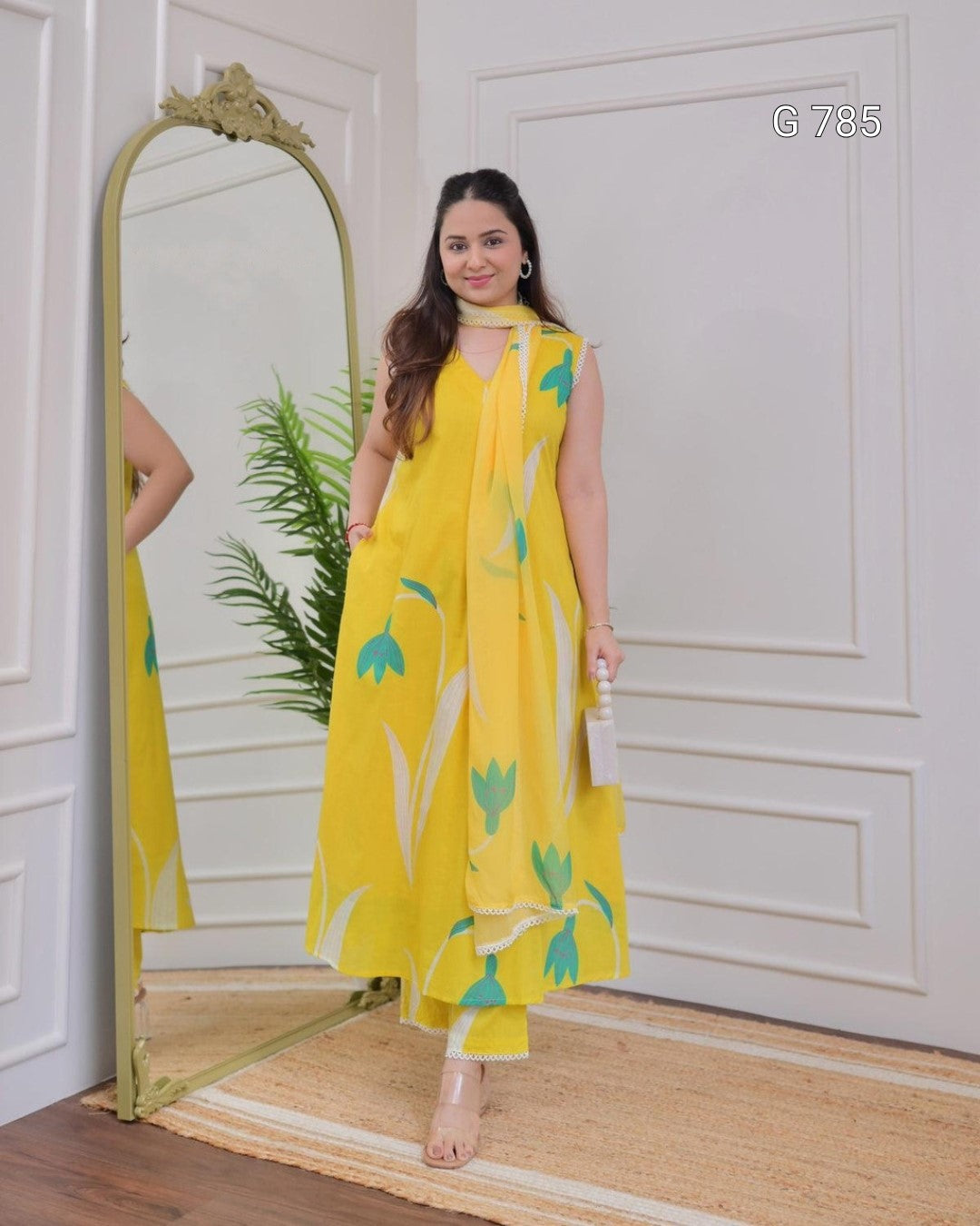 Woman wearing a yellow floral dress standing in front of a full-length mirror.