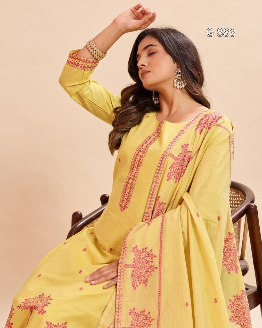 Woman wearing a yellow embroidered traditional outfit with a beige background
