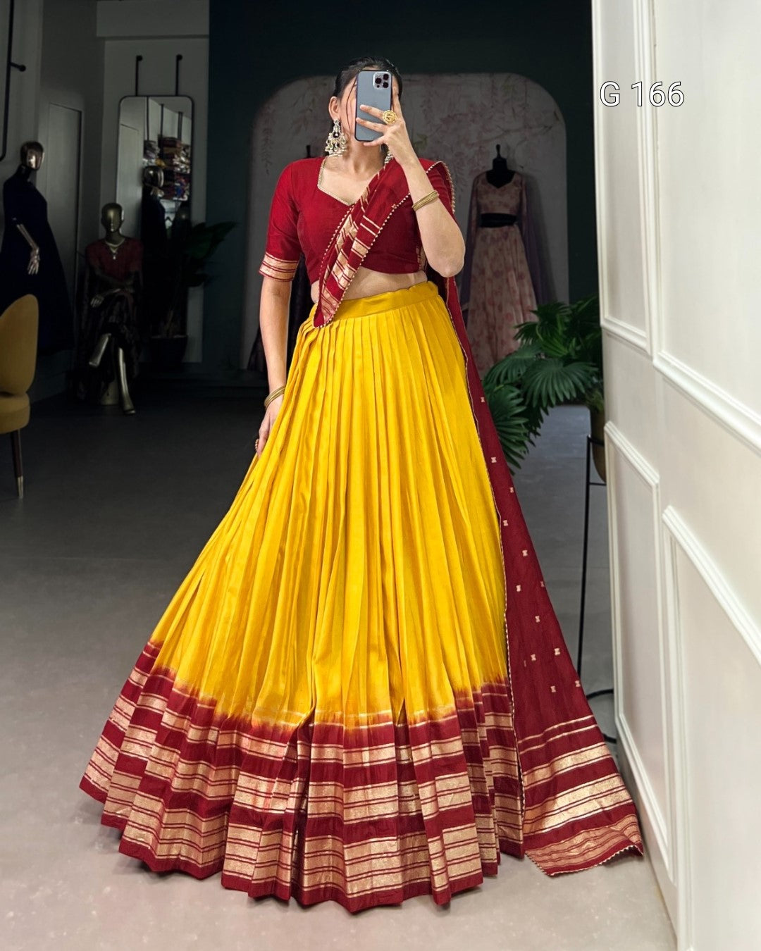 Person wearing a yellow and red traditional outfit in a mirror selfie.