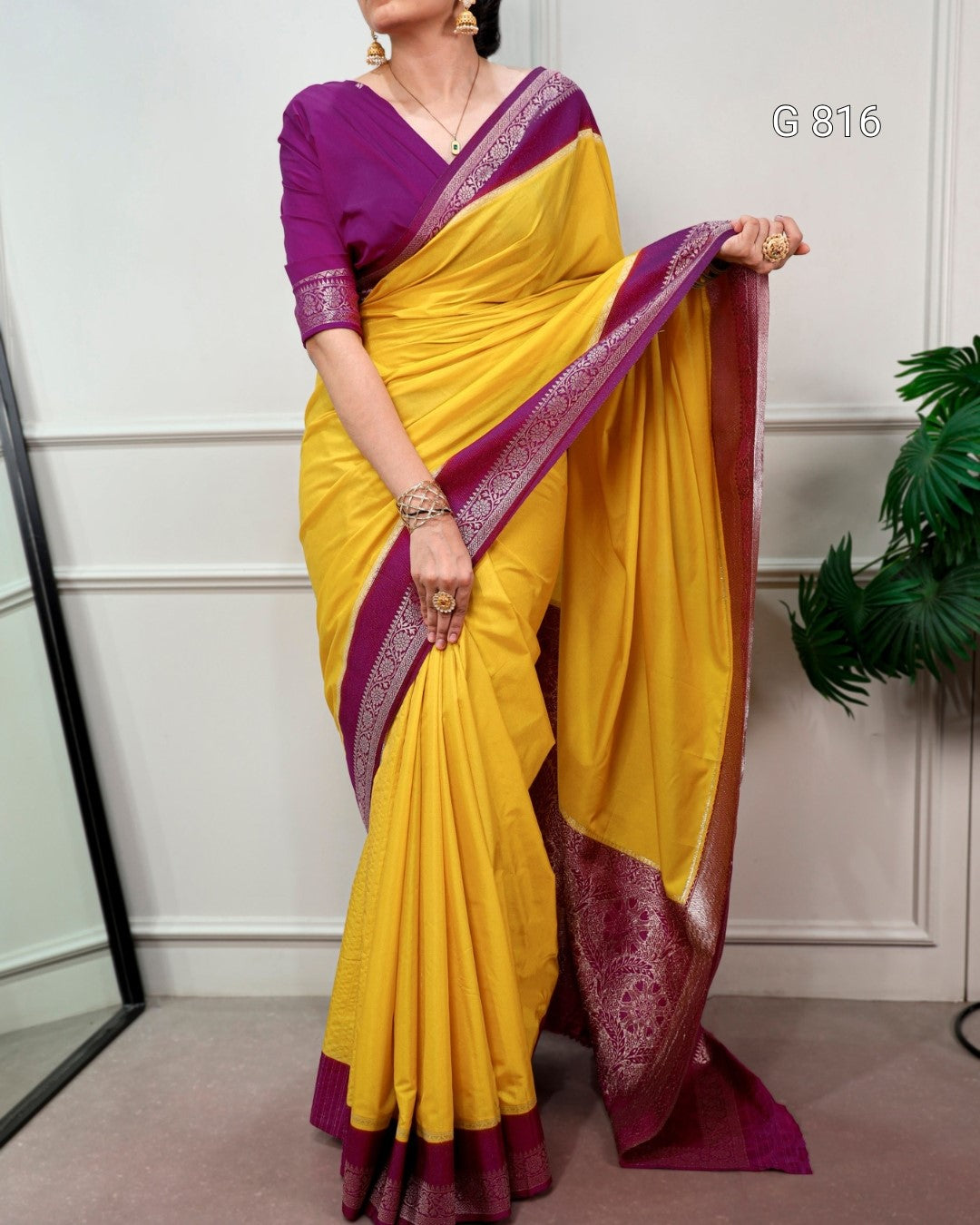 Woman wearing a yellow saree with purple border indoors
