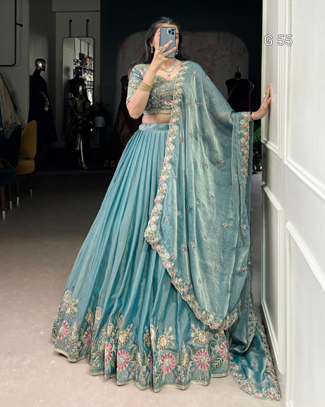 Person wearing a light blue embroidered lehenga with a matching dupatta in a room.
