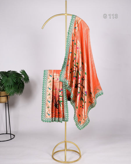 Orange saree with green border on a gold stand against a white background