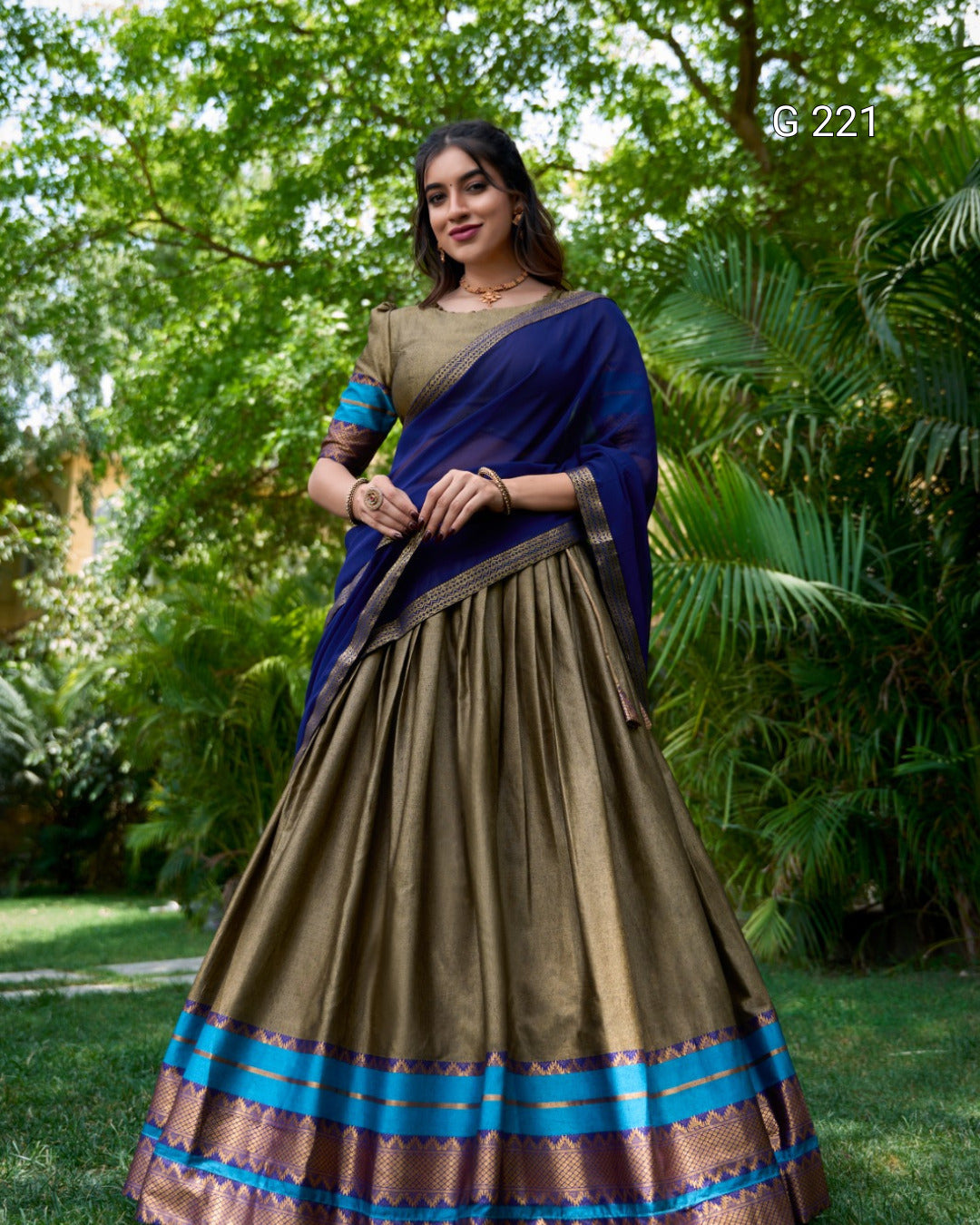 Woman wearing a traditional saree with a blue and green pattern in a garden setting