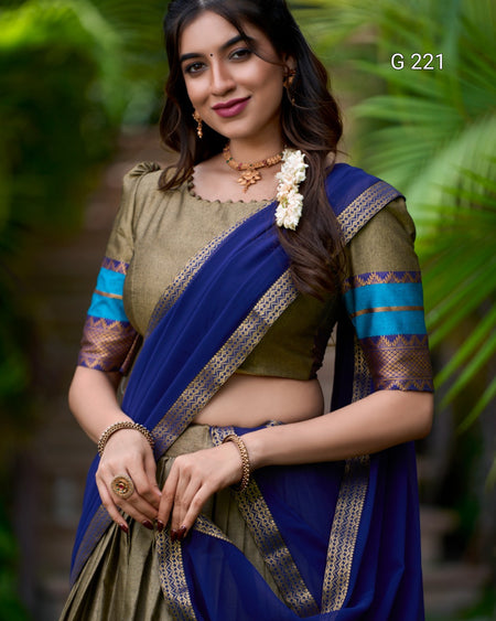 Woman wearing a traditional saree with a blue and green color scheme against a blurred natural background.