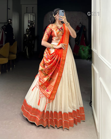 Woman wearing a traditional saree with orange and white colors in an indoor setting.