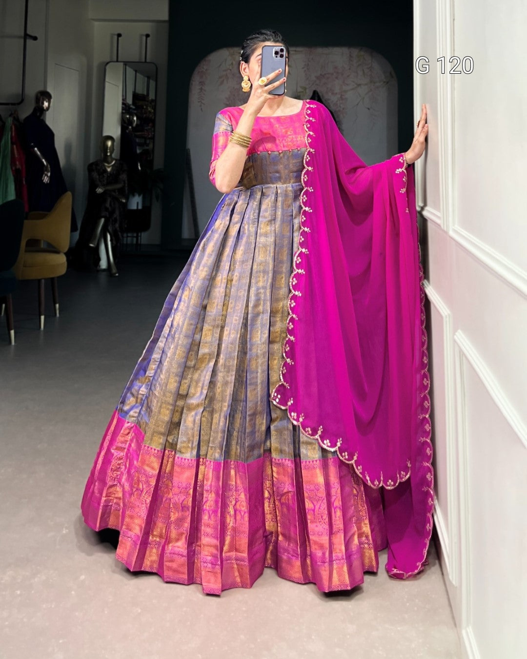 Woman wearing a traditional outfit with a pink and purple saree in an indoor setting.
