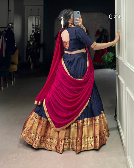 Person wearing a traditional outfit with a red dupatta in a room.