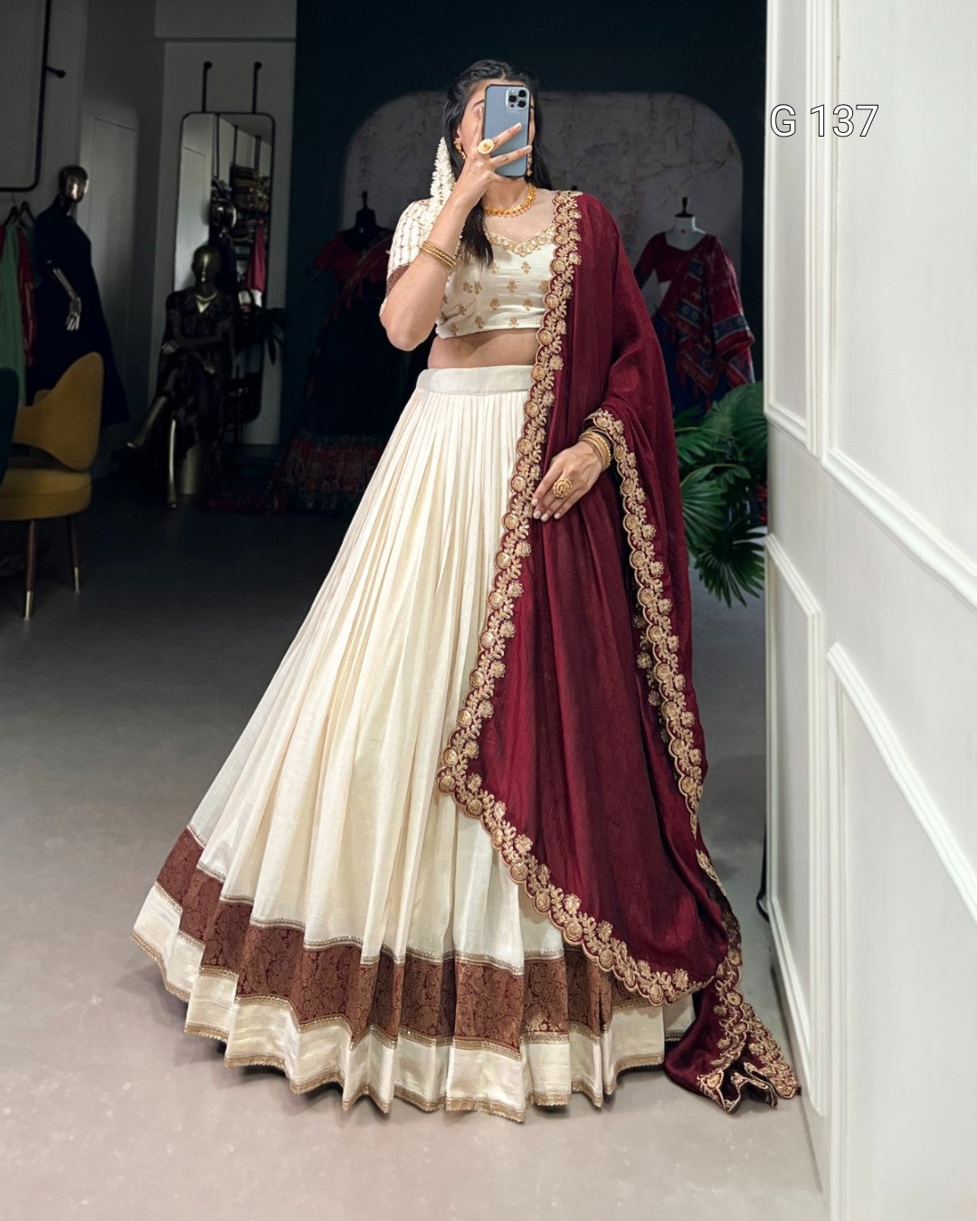 Person wearing a traditional outfit with a maroon dupatta in a room setting.
