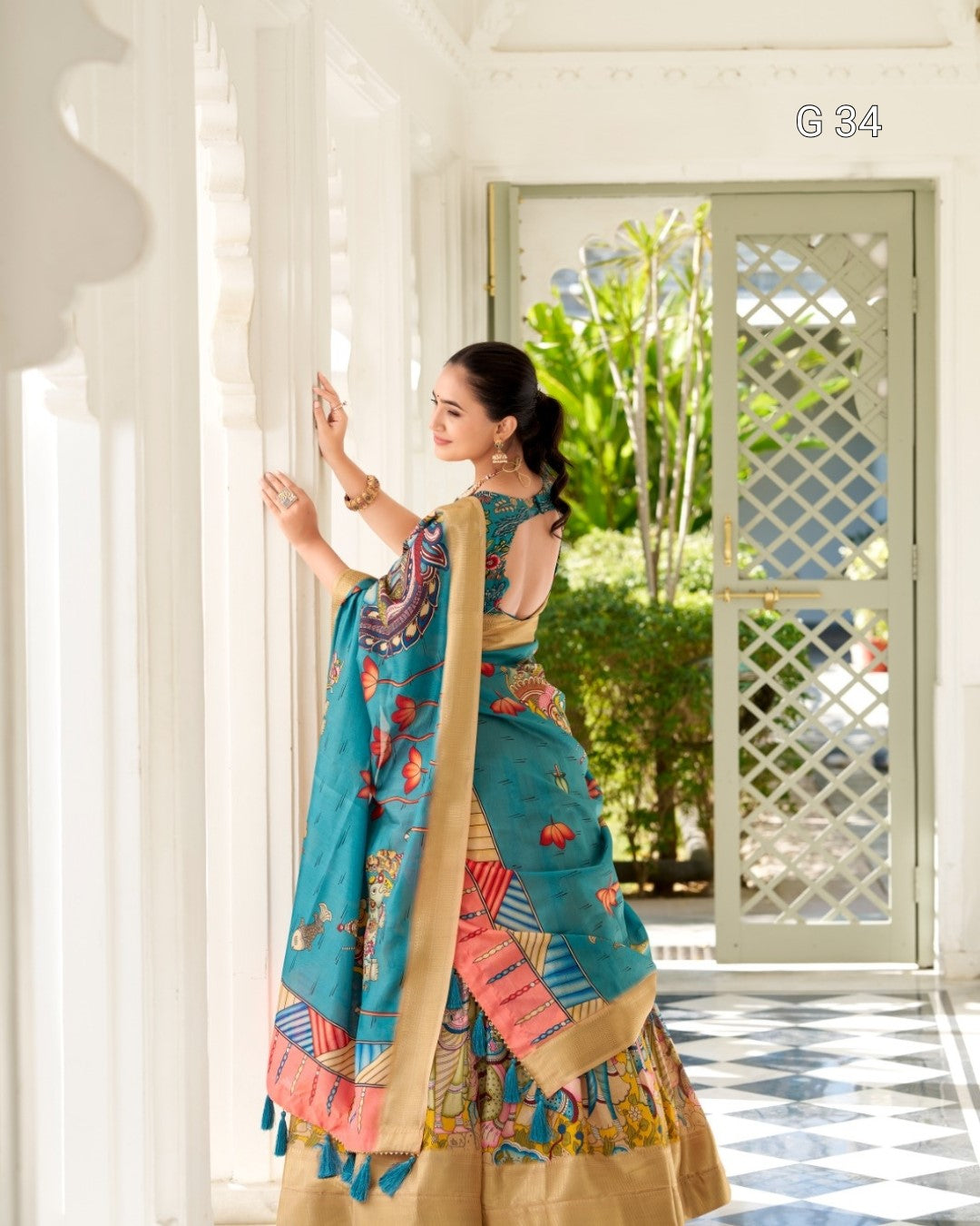 Woman in a colorful traditional outfit standing in a well-lit room with white walls and a checkered floor.