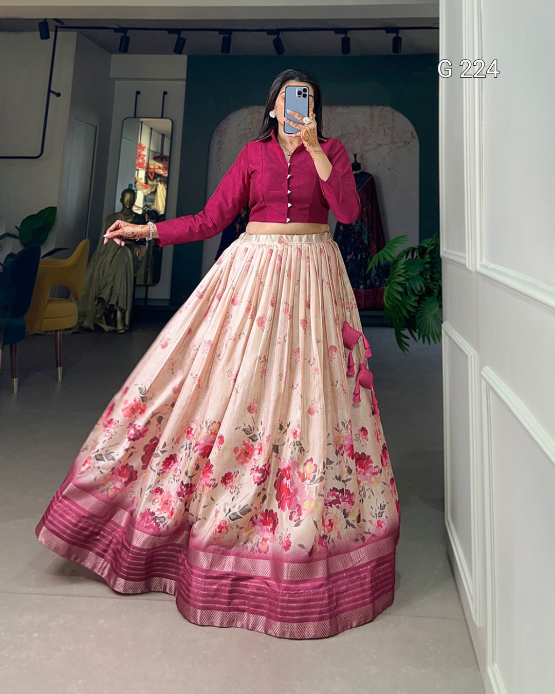 Person wearing a floral skirt and pink top in a room with a mirror.