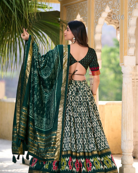 Woman in a traditional green and gold saree with a patterned design, standing outdoors.