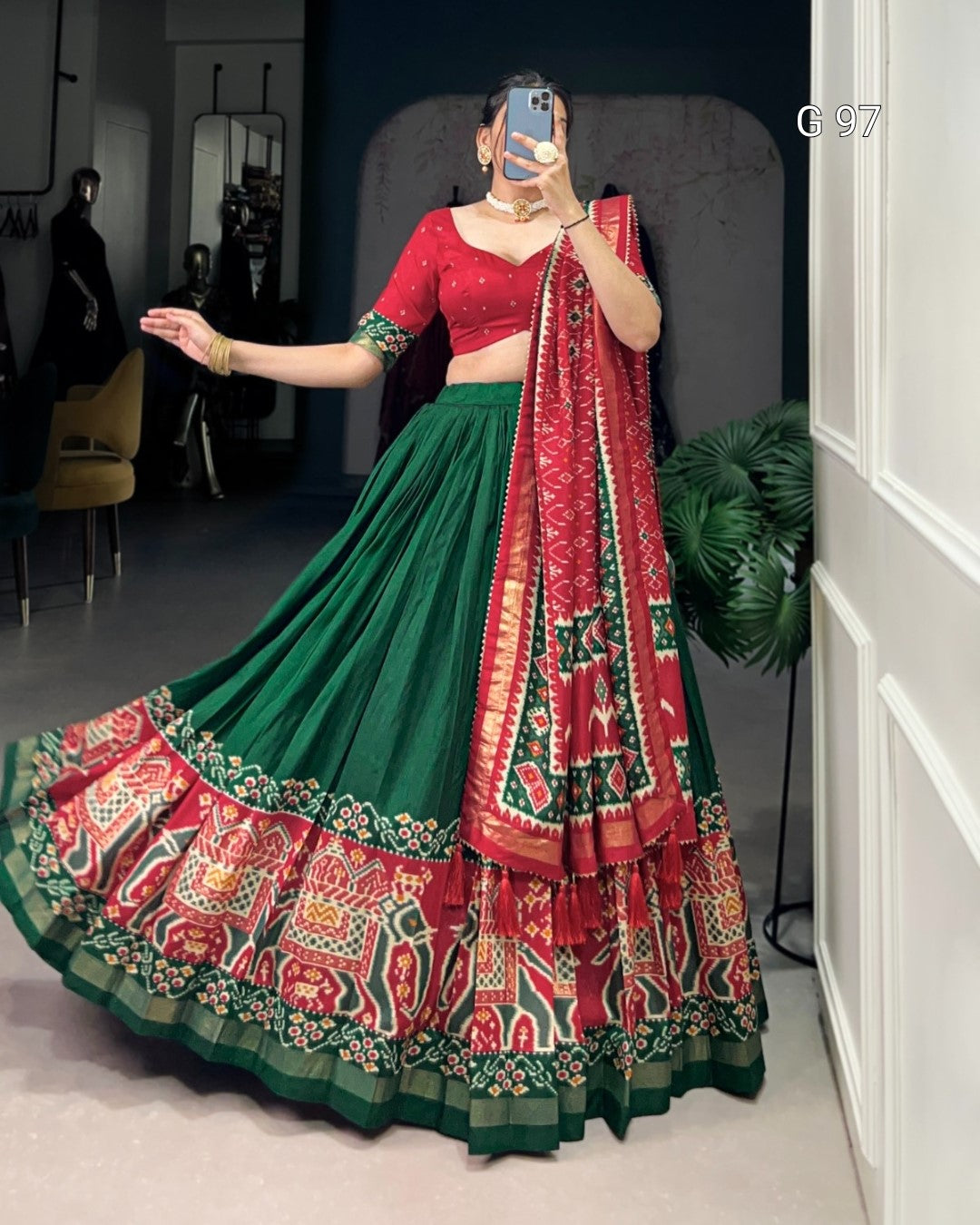 Person wearing a red and green traditional outfit with a patterned dupatta indoors.