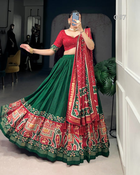 Person wearing a red and green traditional outfit with a patterned dupatta indoors.