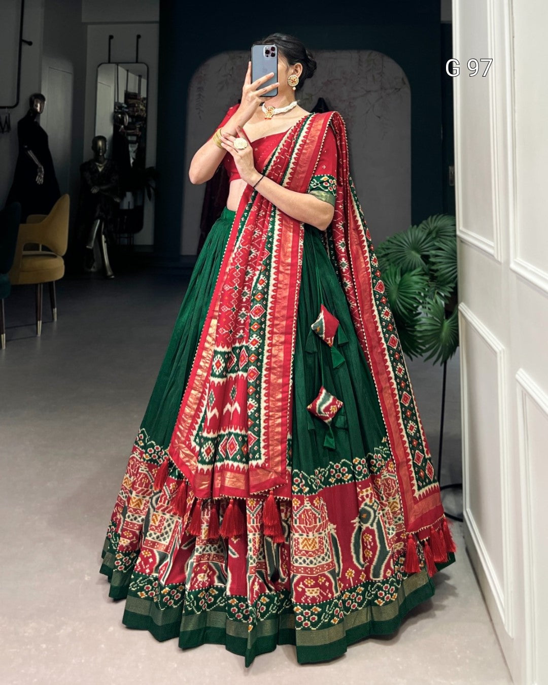Woman in a red and green traditional outfit taking a mirror selfie.