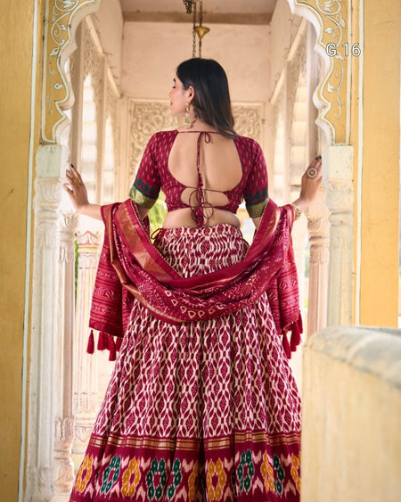 Woman in a traditional red and patterned outfit standing in an ornate doorway.